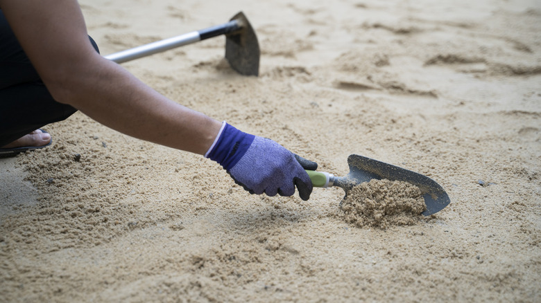 person smoothing sand with trowel