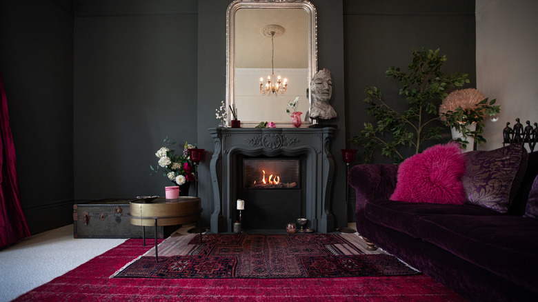 A bold living room with purple and magenta furniture is painted dark charcoal