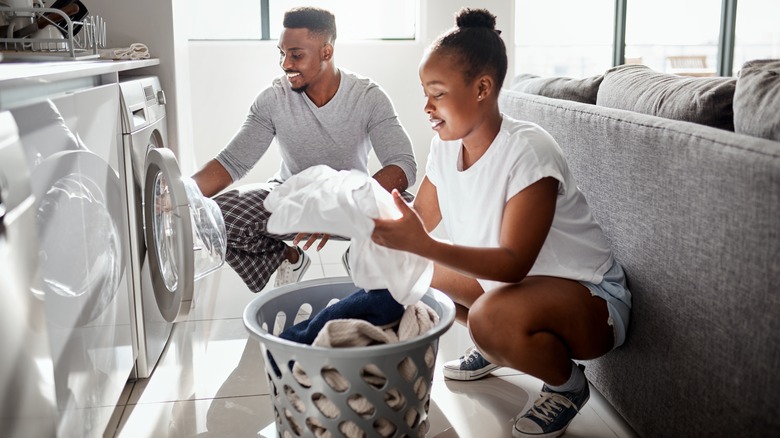 couple placing clothes in washer