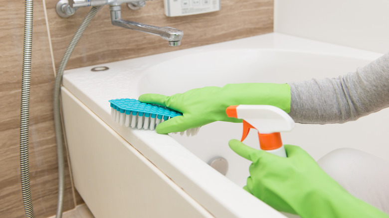 Person scrubs tub with cleaner