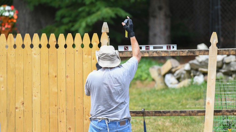 Man installing wooden picket fence