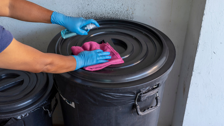 person cleaning trash can