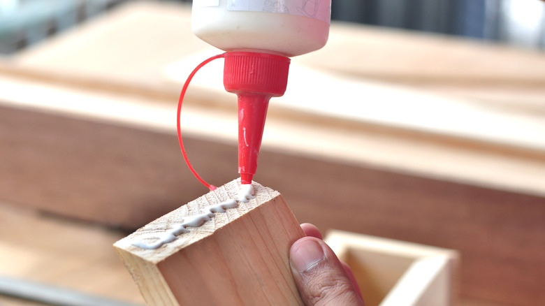 A close up of someone applying glue to a block of wood