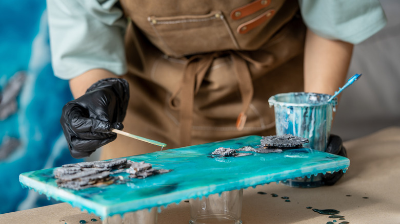 A person applying epoxy resin on a wooden board