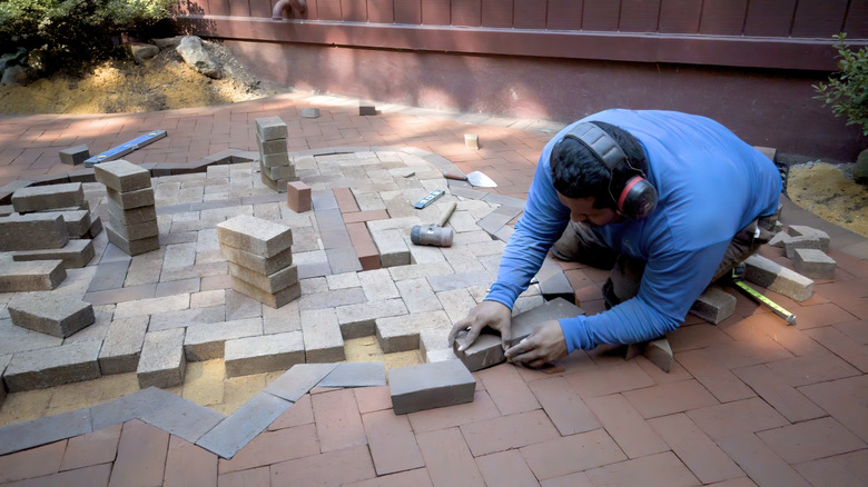 Person laying pavers on a patio