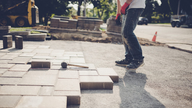 Person installing pavers in a driveway