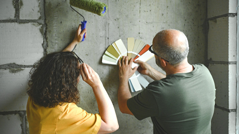 Two people looking at different paint samples, one person holding a paint roller