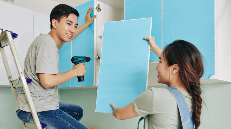 Couple re-installing cabinet doors