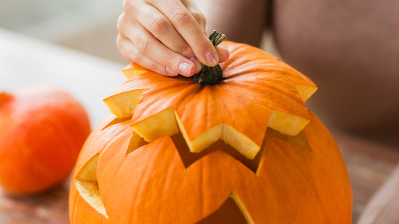 placing pumkin lid on jack-o-lantern