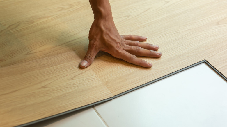 person laying vinyl plank floor