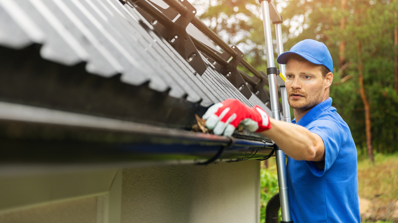 man removing leaves from gutter