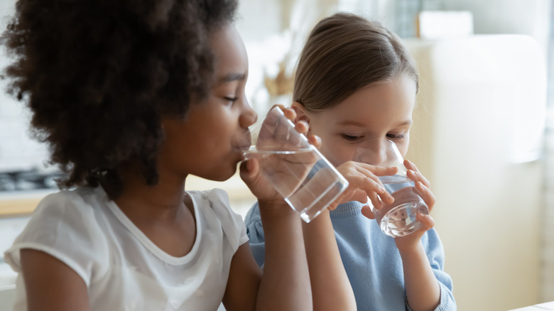 two young girls drinking water from glasses