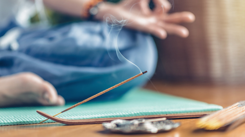 incenses burning while woman meditates