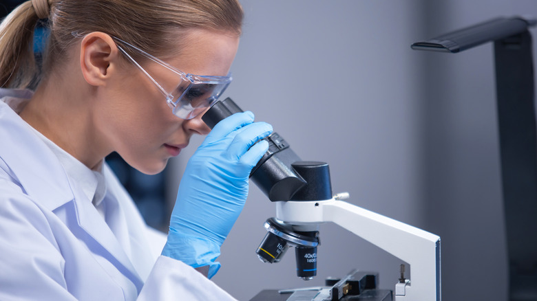 Woman looks through microscope