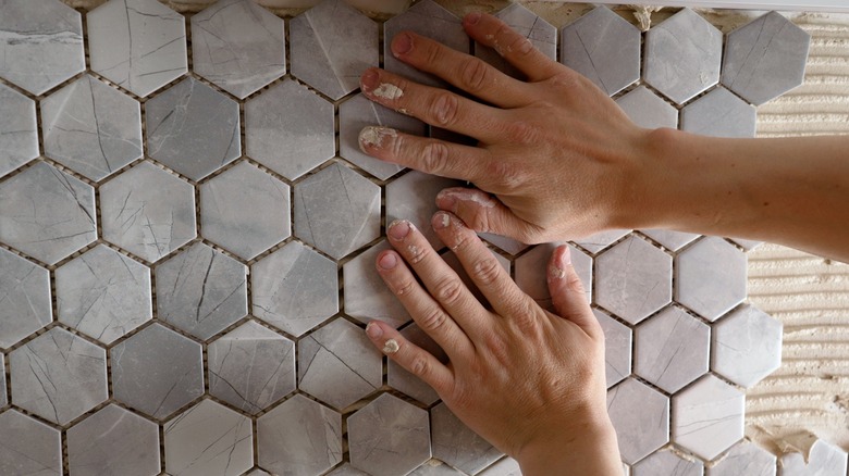 Hands installing tile