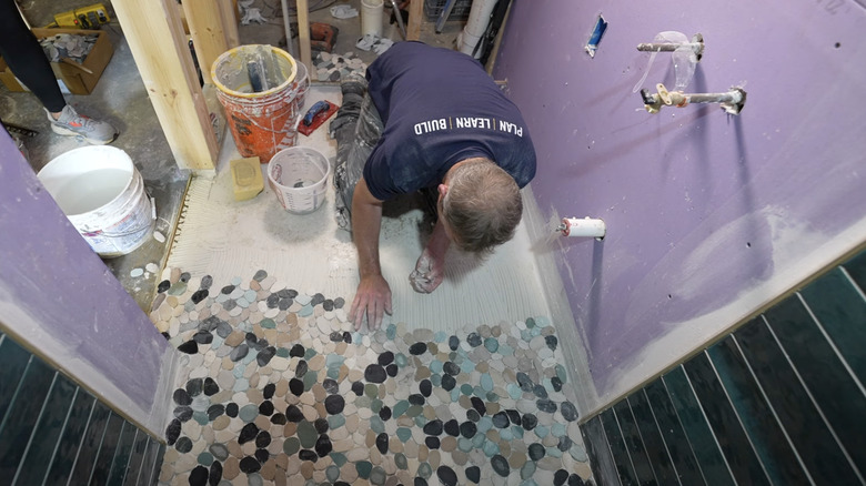 contractor laying pebble shower by hand