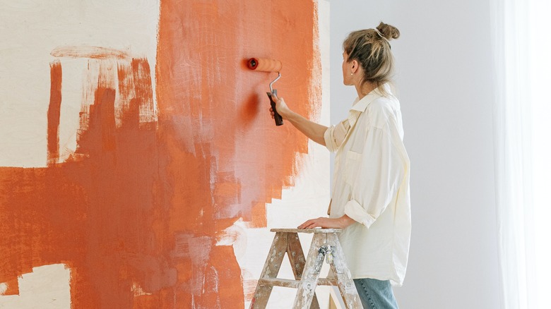 Woman painting wall orange