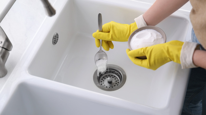 Spooning baking soda into drain