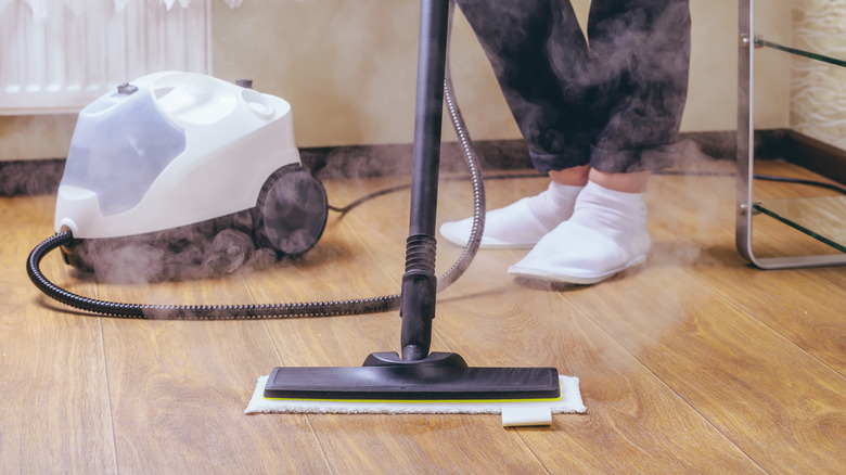 View of person's feet while steam mopping wood floor