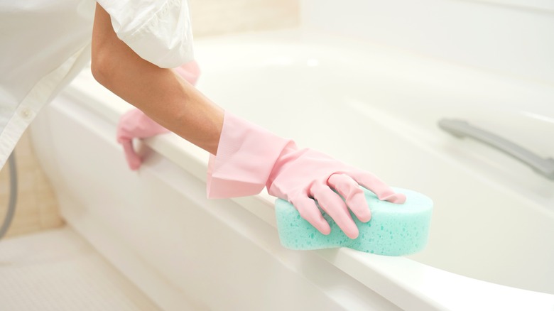 cleaning bathtub with sponge