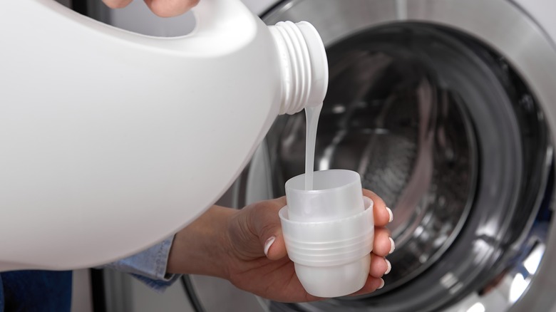 Hands pouring laundry detergent