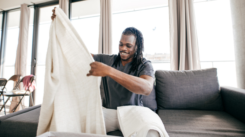 man folding bed sheets