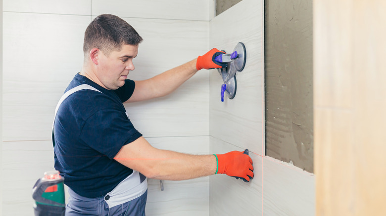 Man installing large bathroom tiles