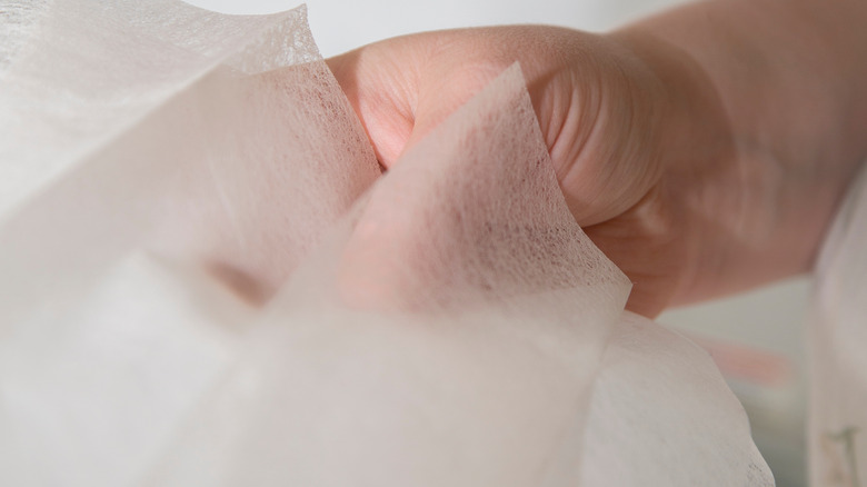 Hand holding dryer sheet closeup