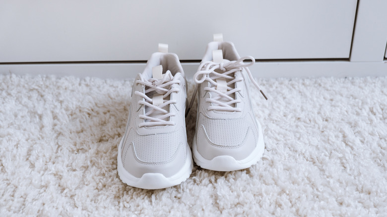 pair of white sneakers on carpet floor