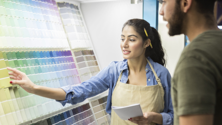 A woman helps a man choose a paint shade.