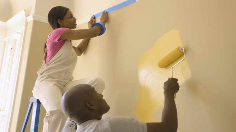 Two people repaint their wall.