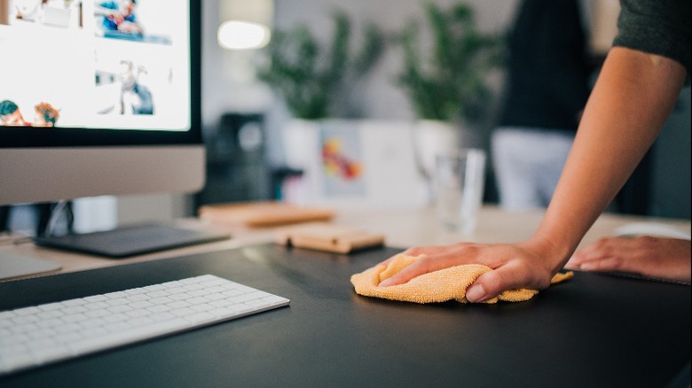 Person cleaning computer desk pad