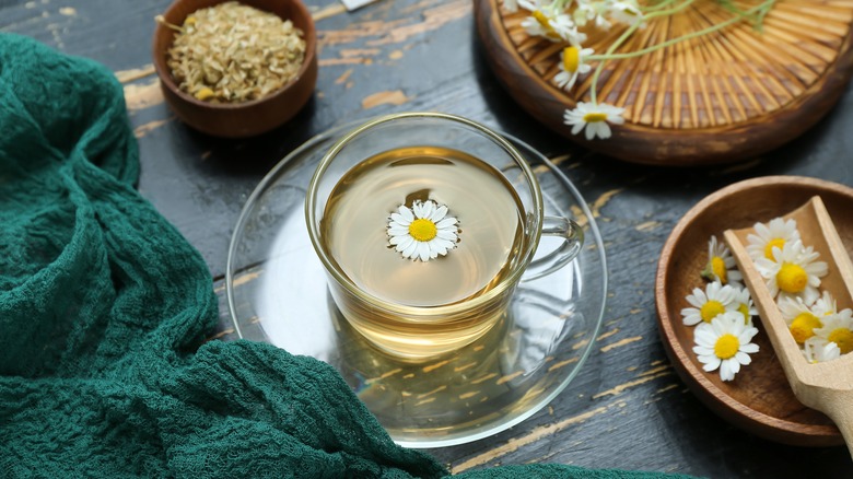 Cup of chamomile tea and dried chamomile flowers