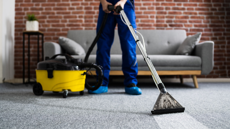 Person cleaning carpet with steam cleaner