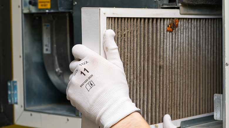 Hand with a white glove replacing HVAC air filter