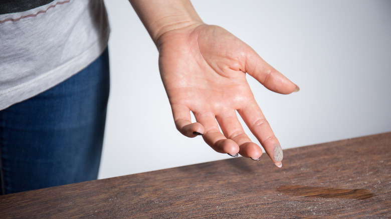 Woman's finger with dust from a dusty table top