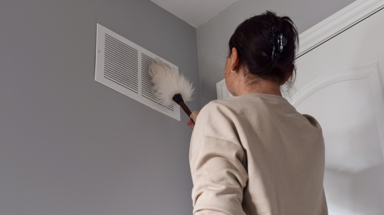 Woman dusting air vent 