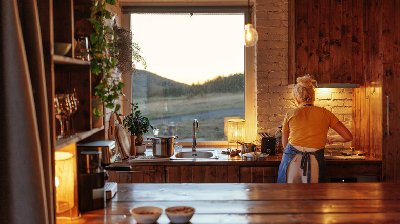 Person working in wooden kitchen with lamps on the counter