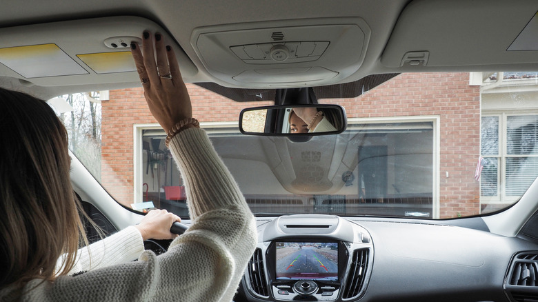 Woman in car using remote to close garage door