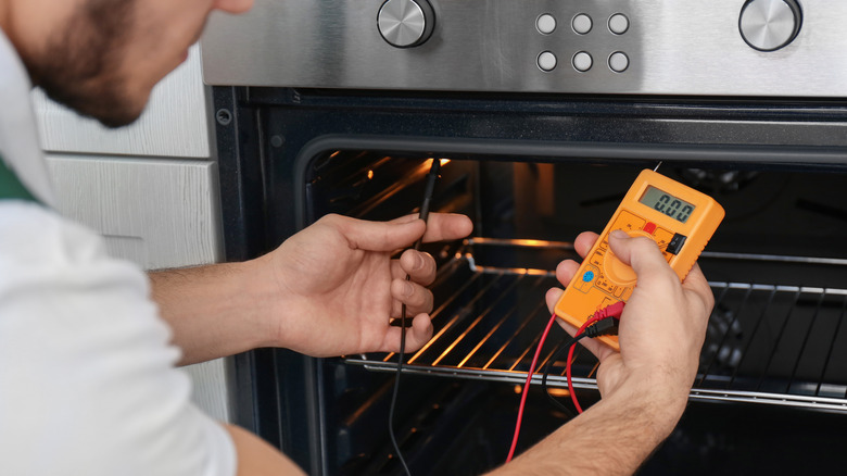 man checks oven with multimeter