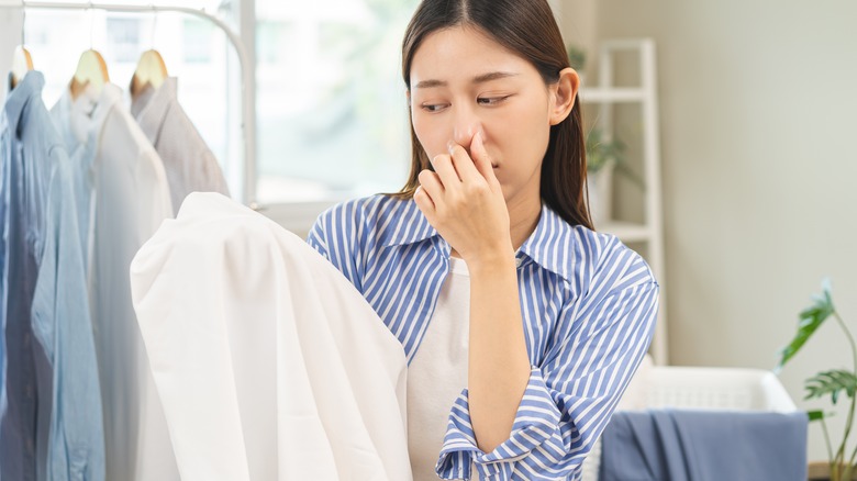 Woman holds nose at stinky laundry