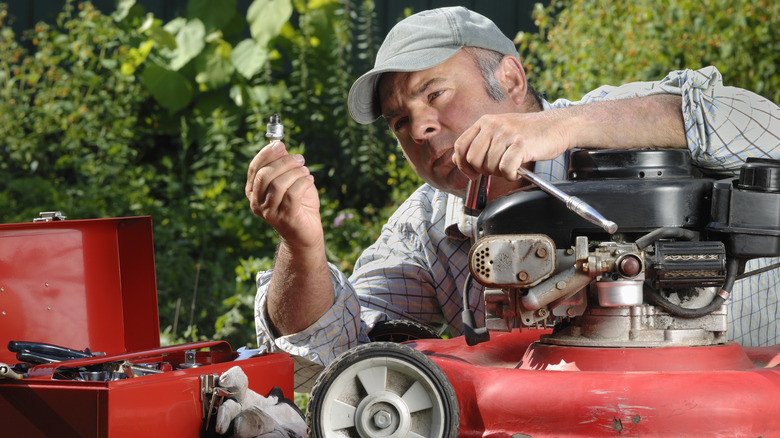 man changing spark plug on mower