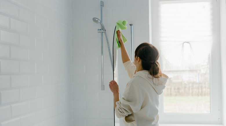 woman cleaning glass shower wall