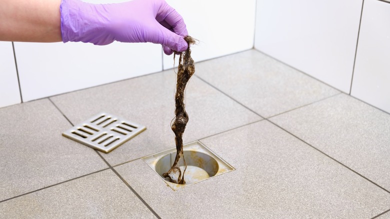 https://www.housedigest.com/img/gallery/why-your-shower-drain-smells-like-sewage-and-how-to-fix-it/get-that-gunk-out-of-your-drain-1681738305.jpg