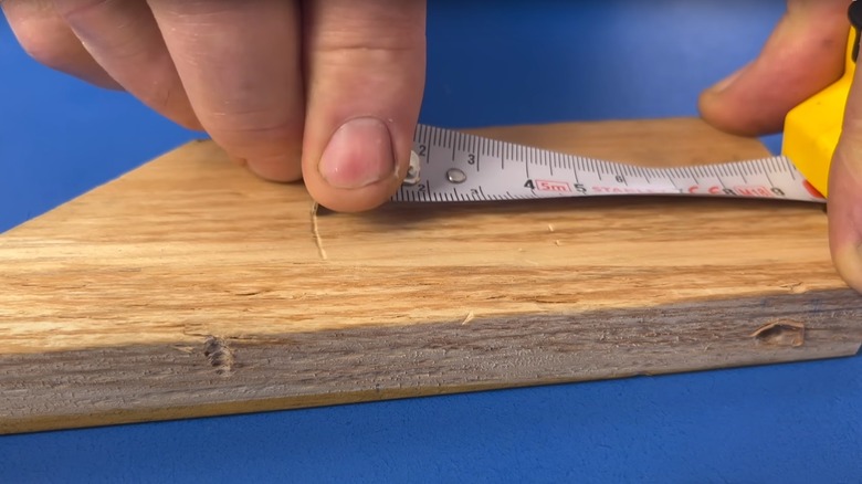 person marking wood with tape measure
