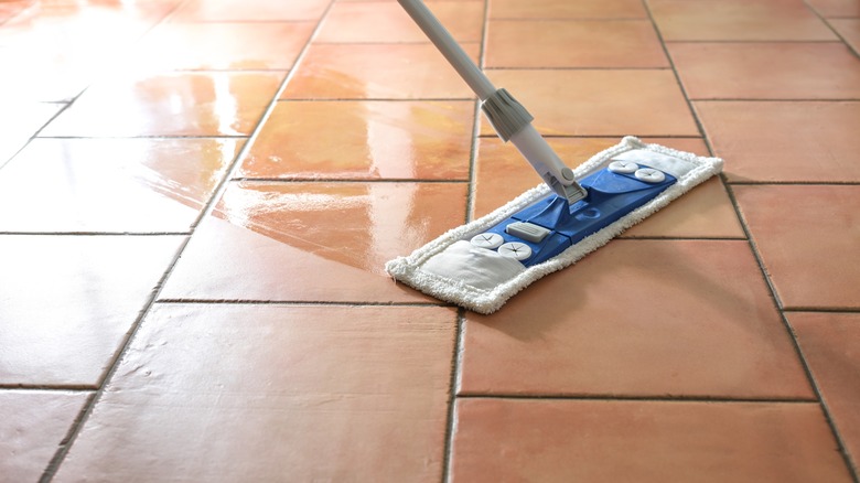 Someone mopping tile floor with a terry cloth mop cover