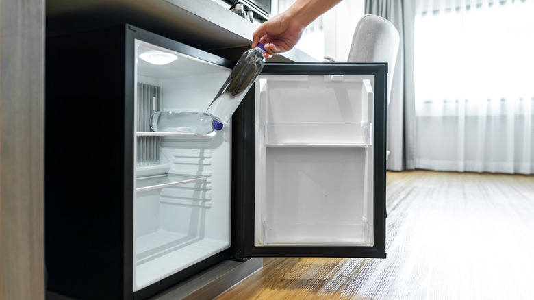 Person taking bottle out of under counter fridge.