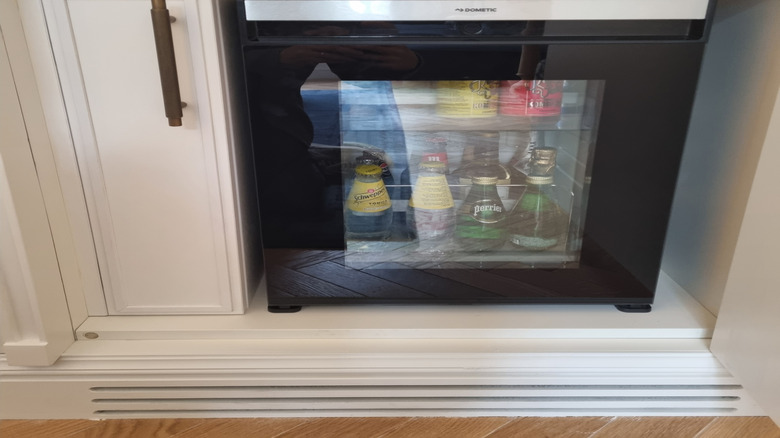 Very full beverage fridge under counter.