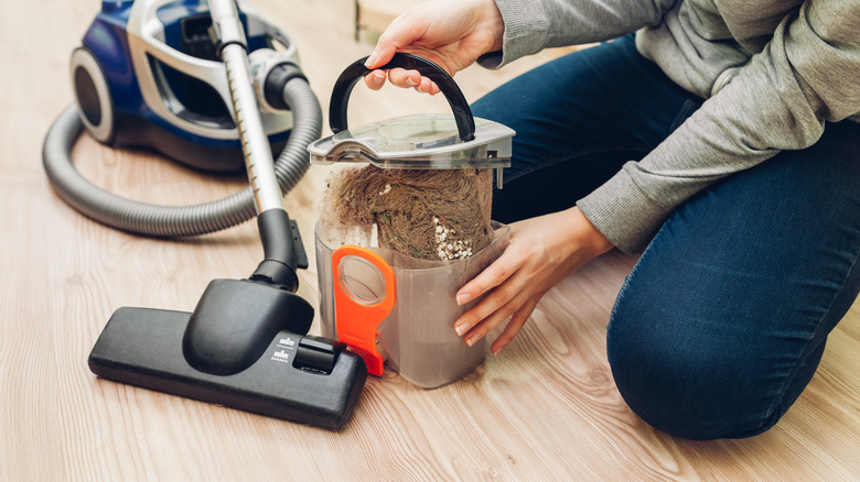 person emptying full vacuum canister