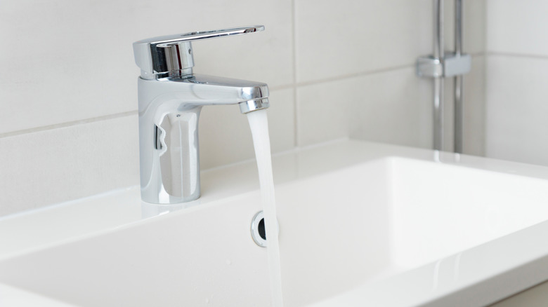 Water flows from a faucet into a white porcelain sink